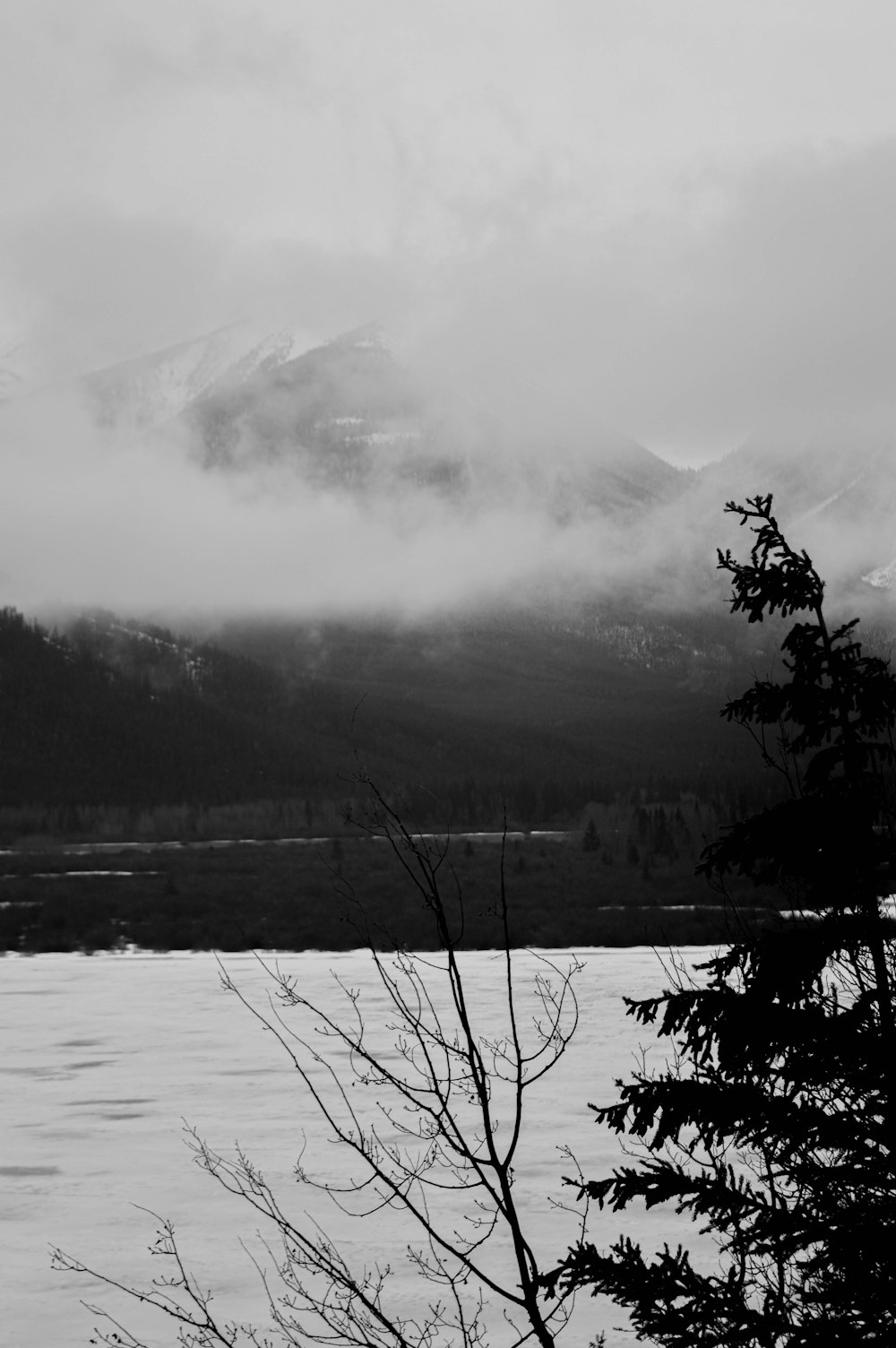 a black and white photo of a lake and mountains