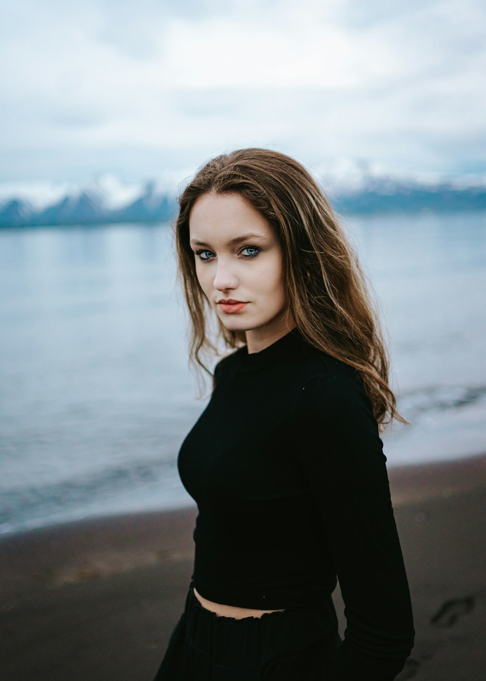 eine schöne junge Frau, die auf einem Strand steht