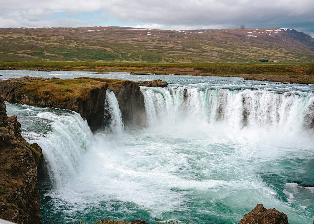 a large waterfall with a man standing on top of it