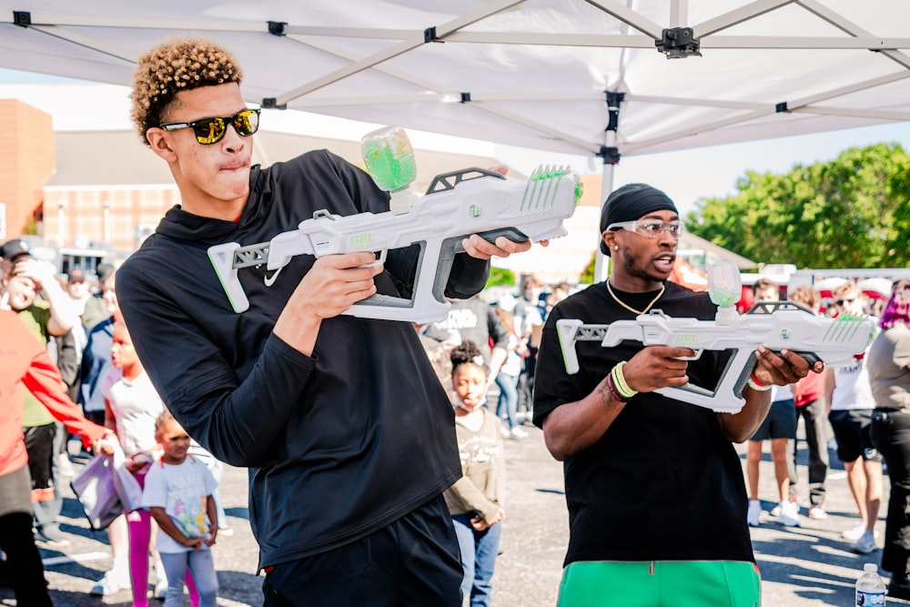 a couple of men standing next to each other holding nerf guns