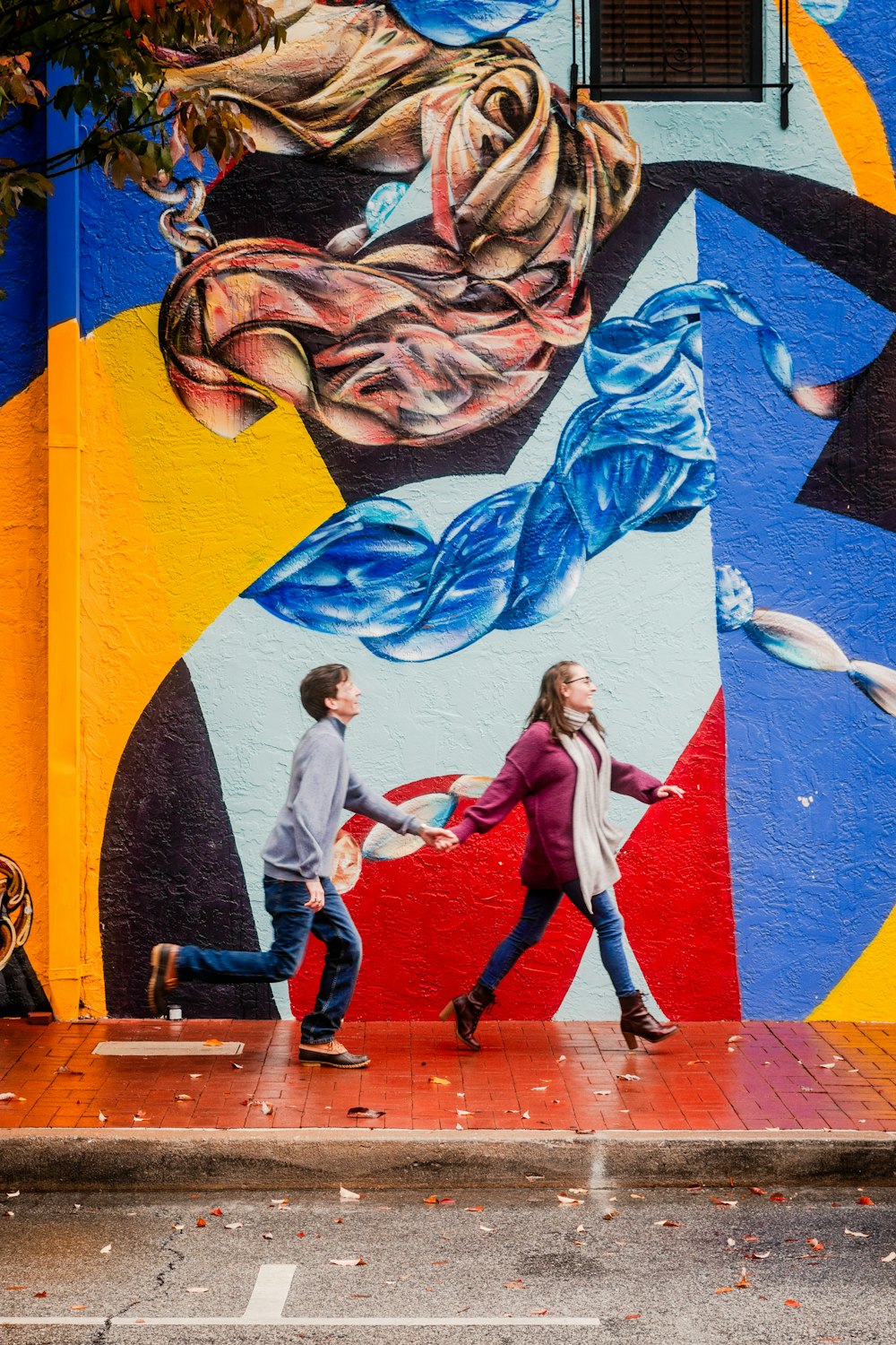 a couple of people walking past a colorful wall