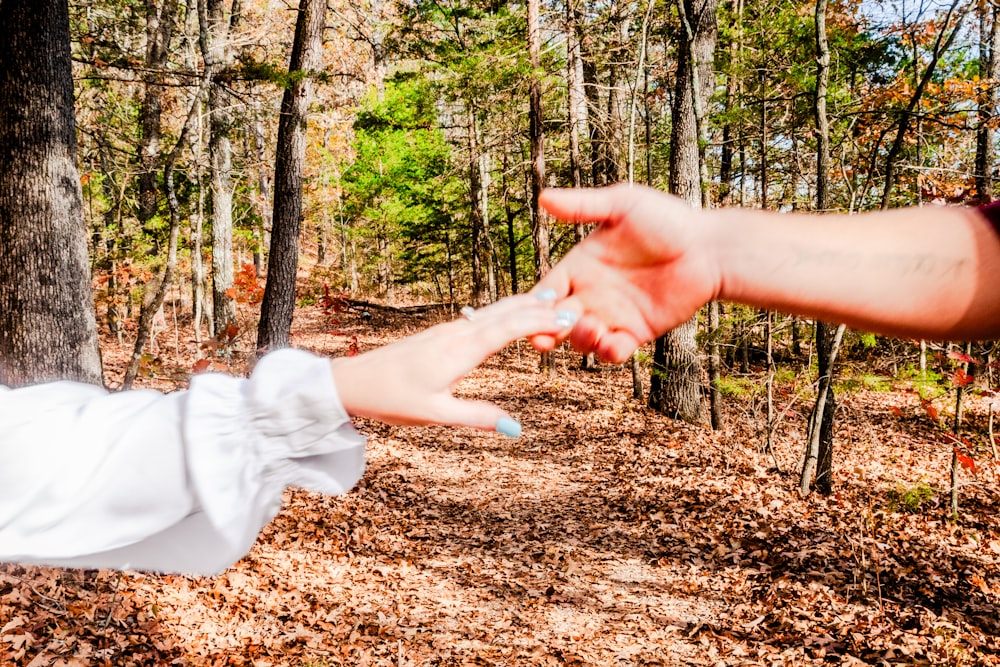 a woman reaching out her hand to a man in the woods