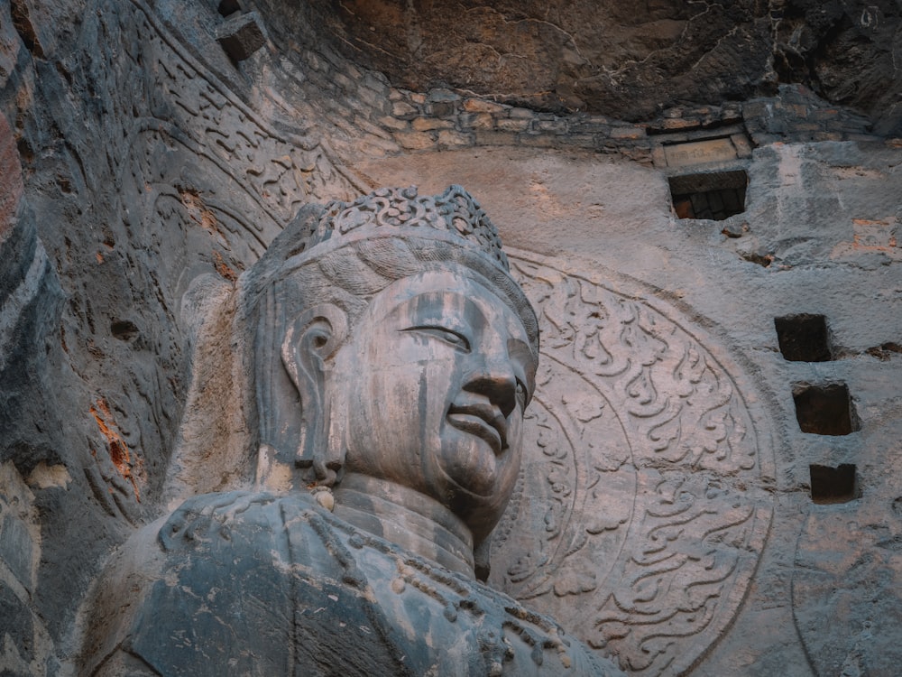 a statue of a buddha in front of a stone wall