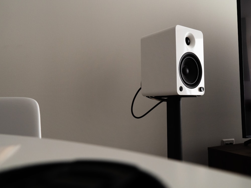 a white speaker sitting on top of a table next to a tv