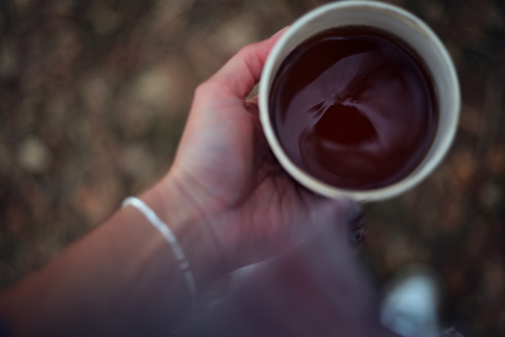 a person holding a cup of coffee in their hand