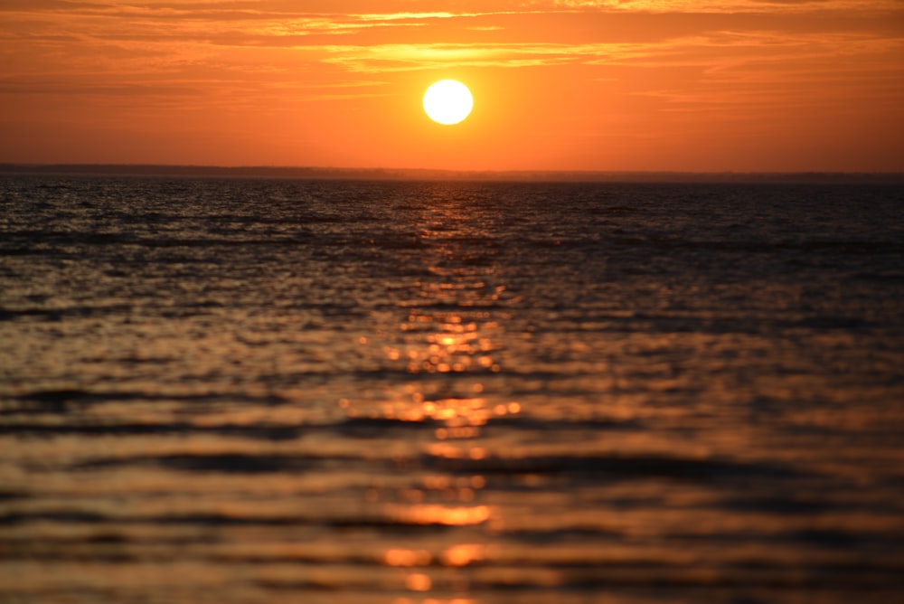 the sun is setting over the ocean on a cloudy day