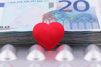 a red heart sitting on top of a pile of money