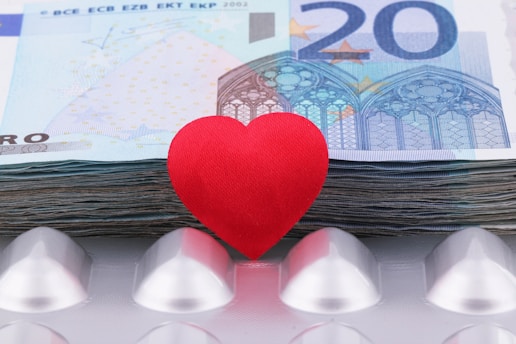 a red heart sitting on top of a pile of money