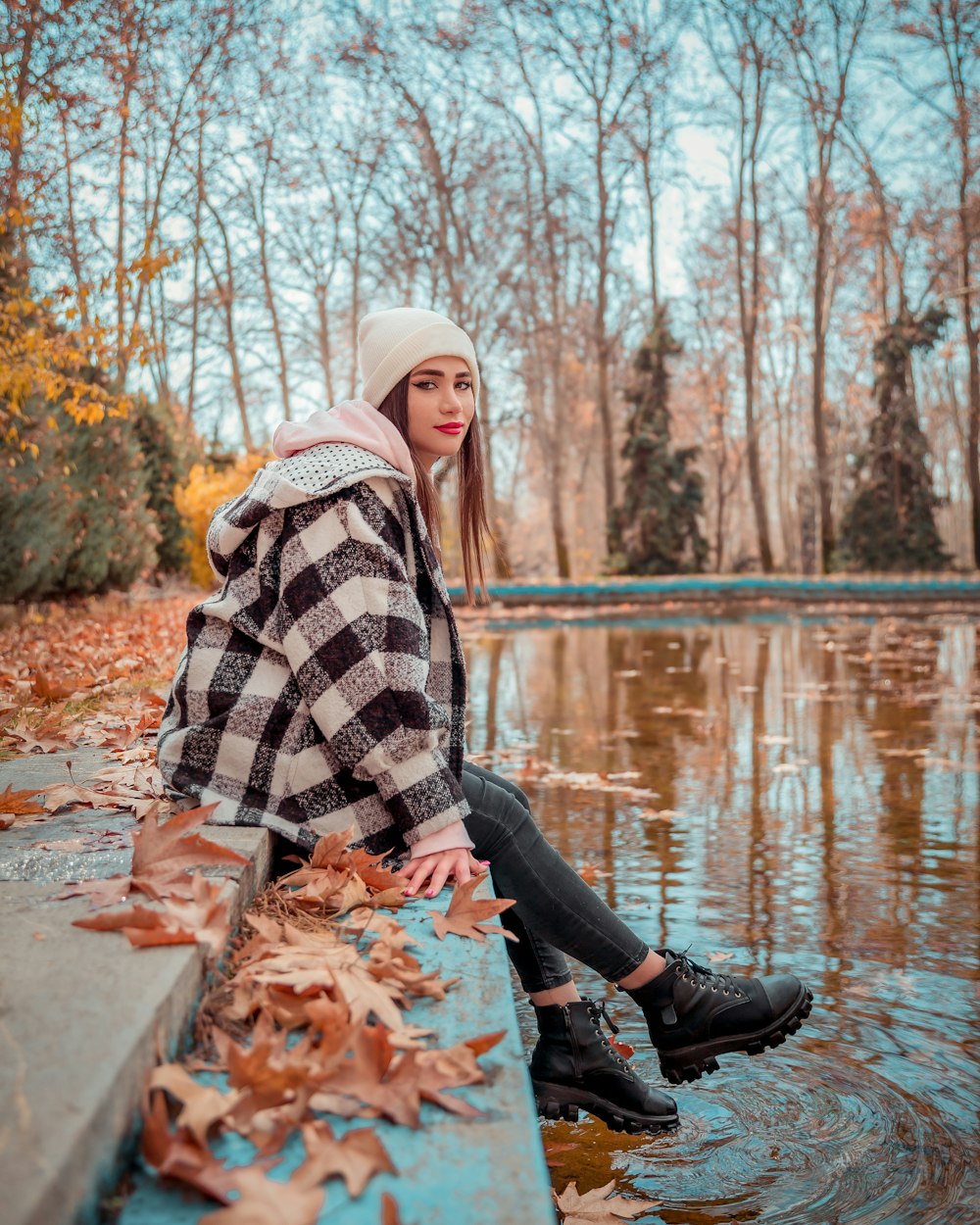 a woman sitting on a ledge next to a body of water