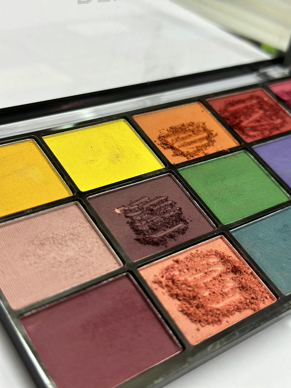 a close up of a makeup palette with a mirror in the background