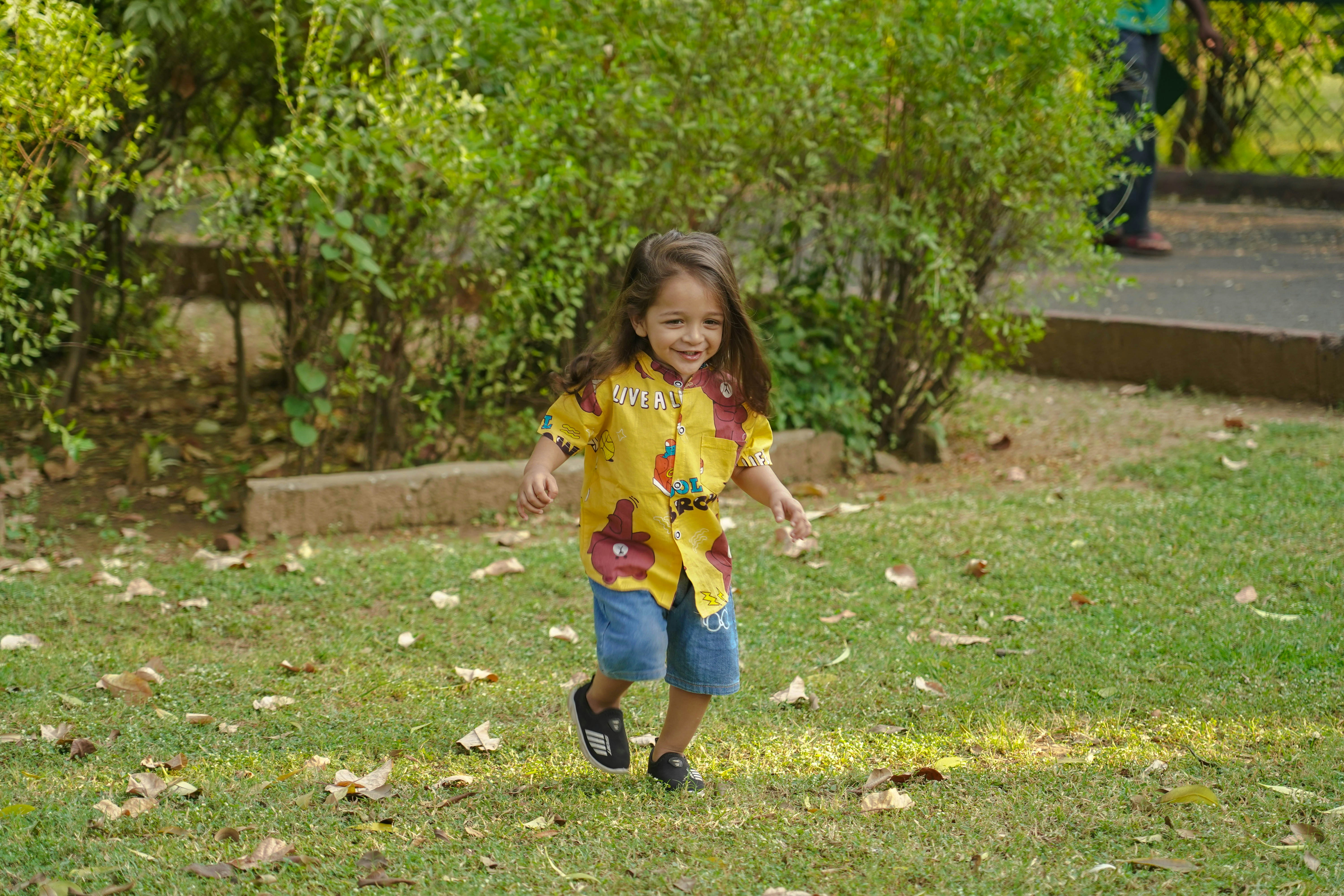 a little girl running in the grass with a frisbee