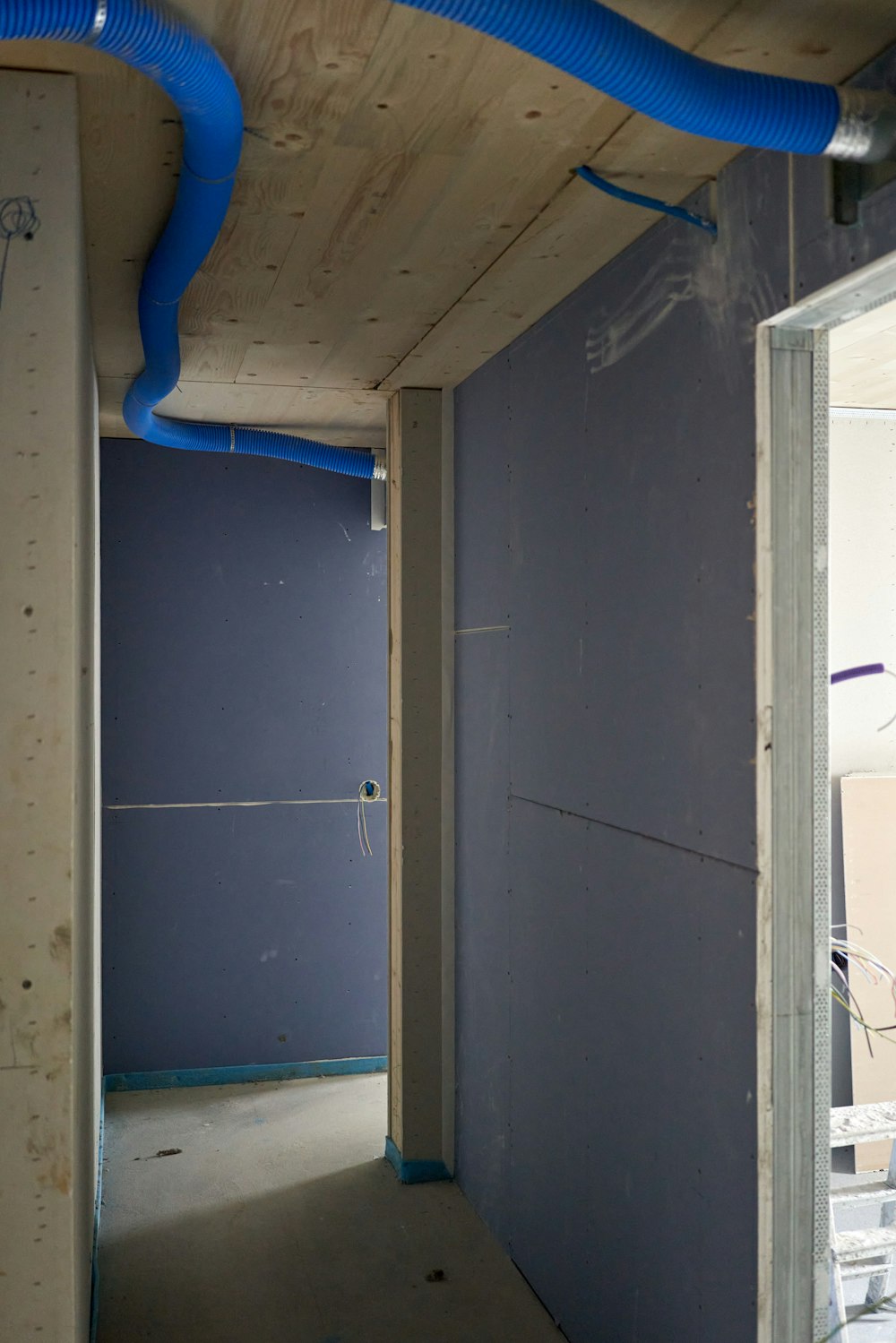 una habitación inacabada con una tubería azul que corre por la pared