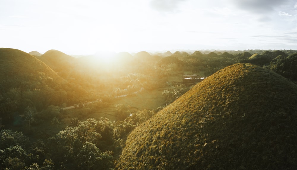 the sun shines through the clouds over the hills