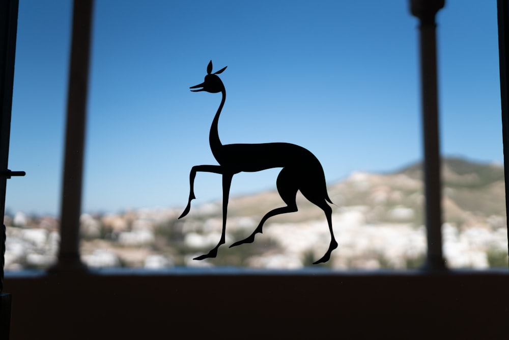 a silhouette of a giraffe is seen through a window