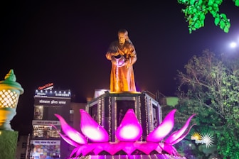 a statue of a man standing on top of a flower