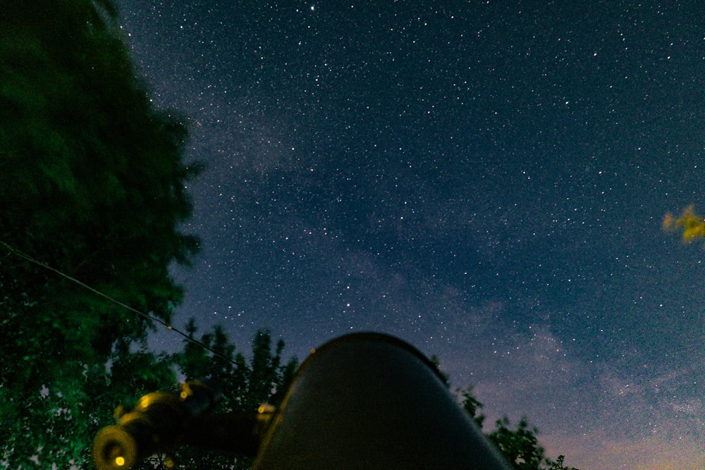 um céu noturno com estrelas e um telescópio