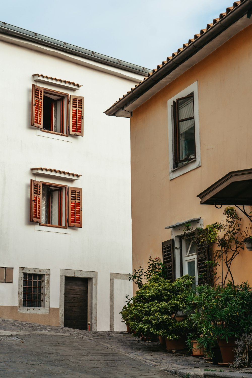 a white building with red shutters and a red fire hydrant