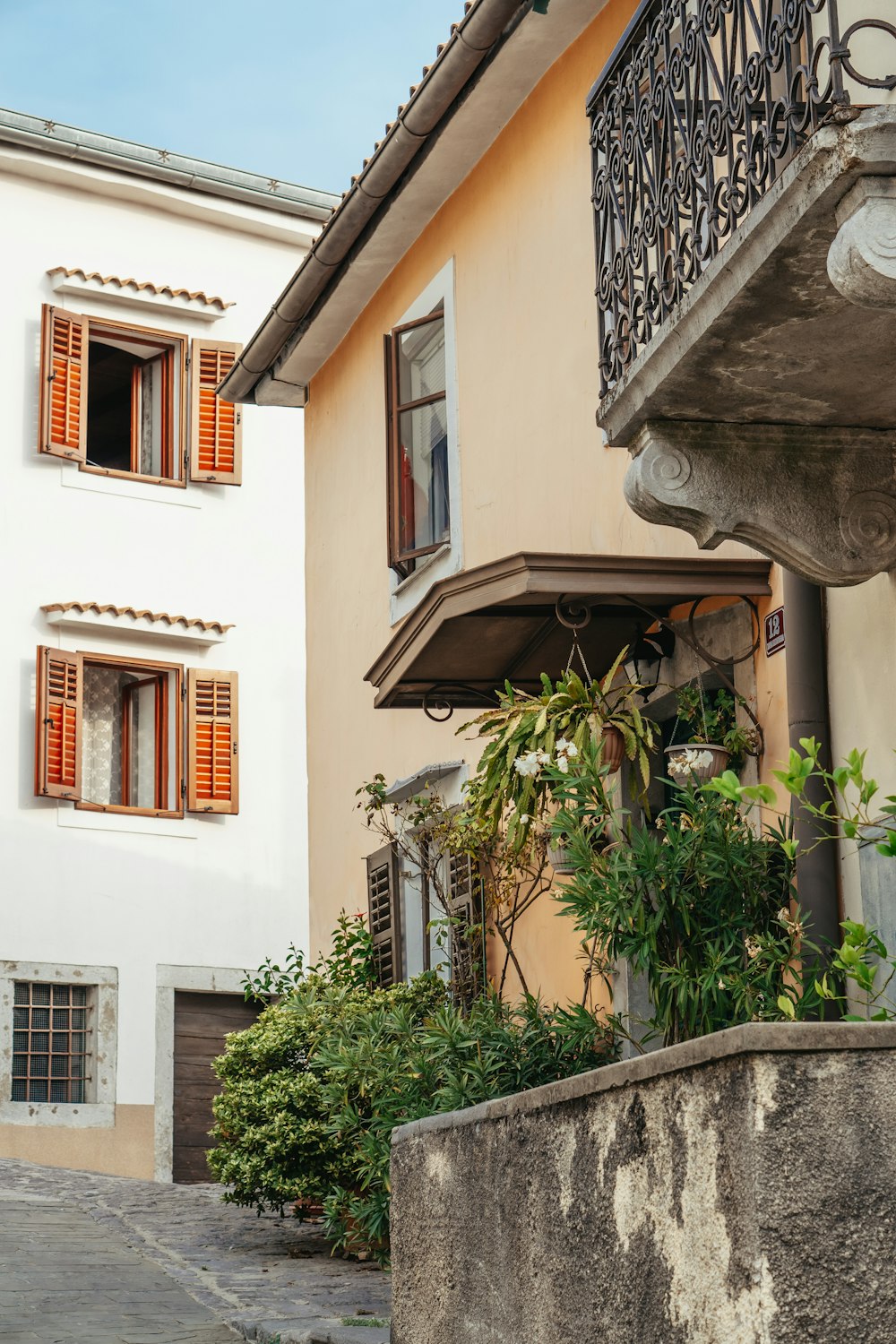 a white building with a balcony and orange shutters