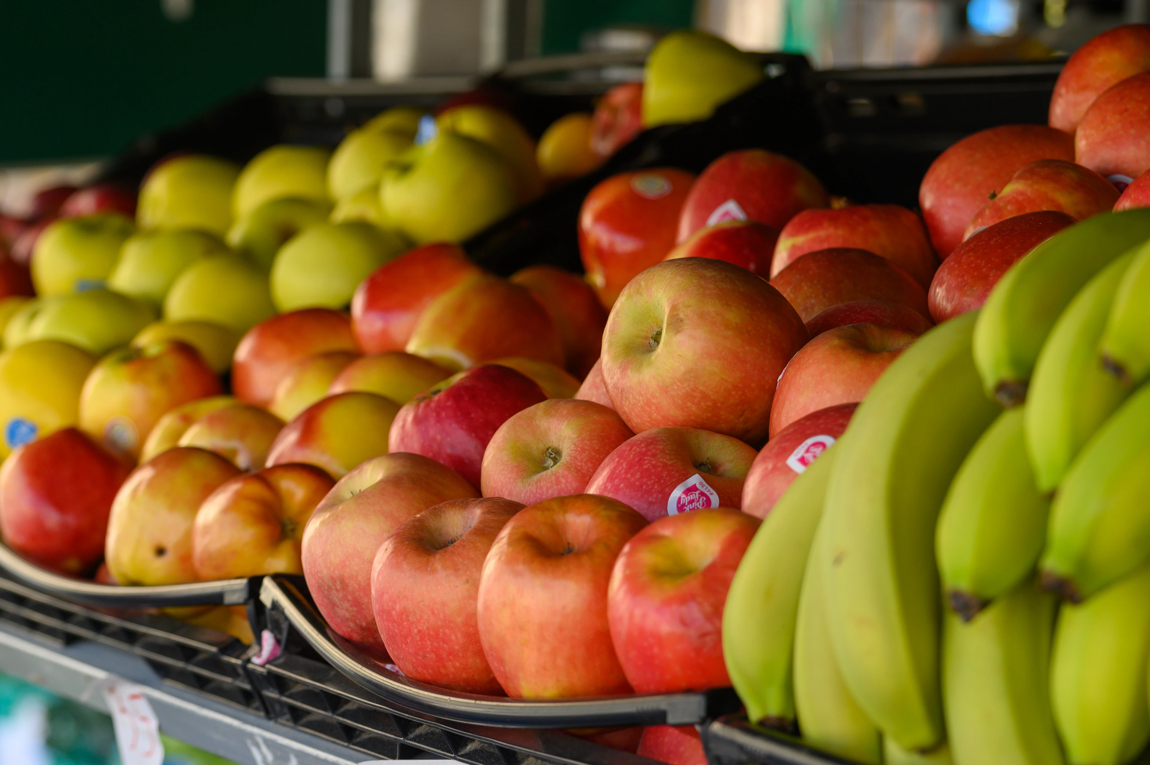 Crates of red and green apples and bunches of bananas stacked on a greengrocer's market stall in Pembroke, Malta
