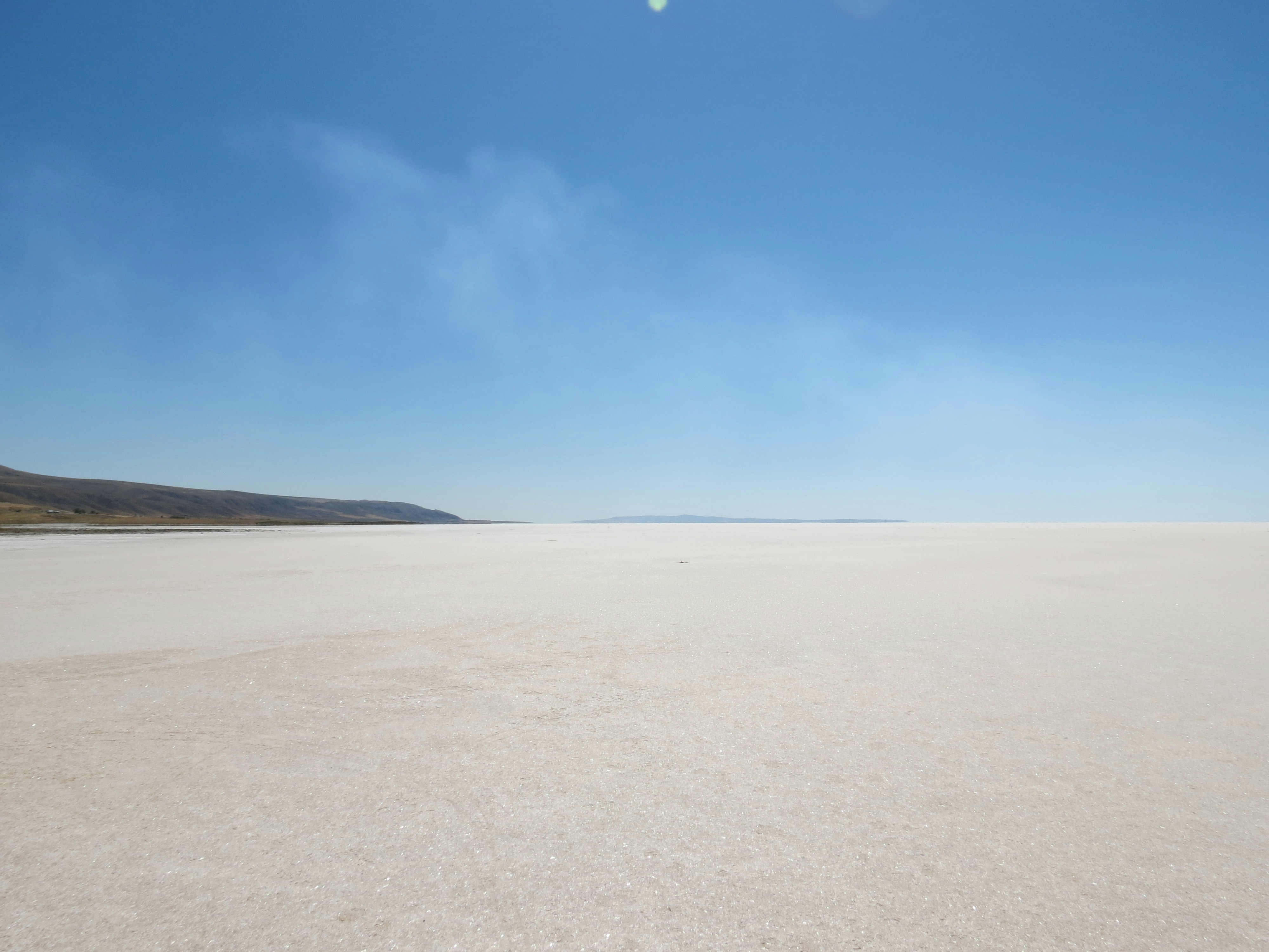 a vast expanse of white sand with a blue sky in the background