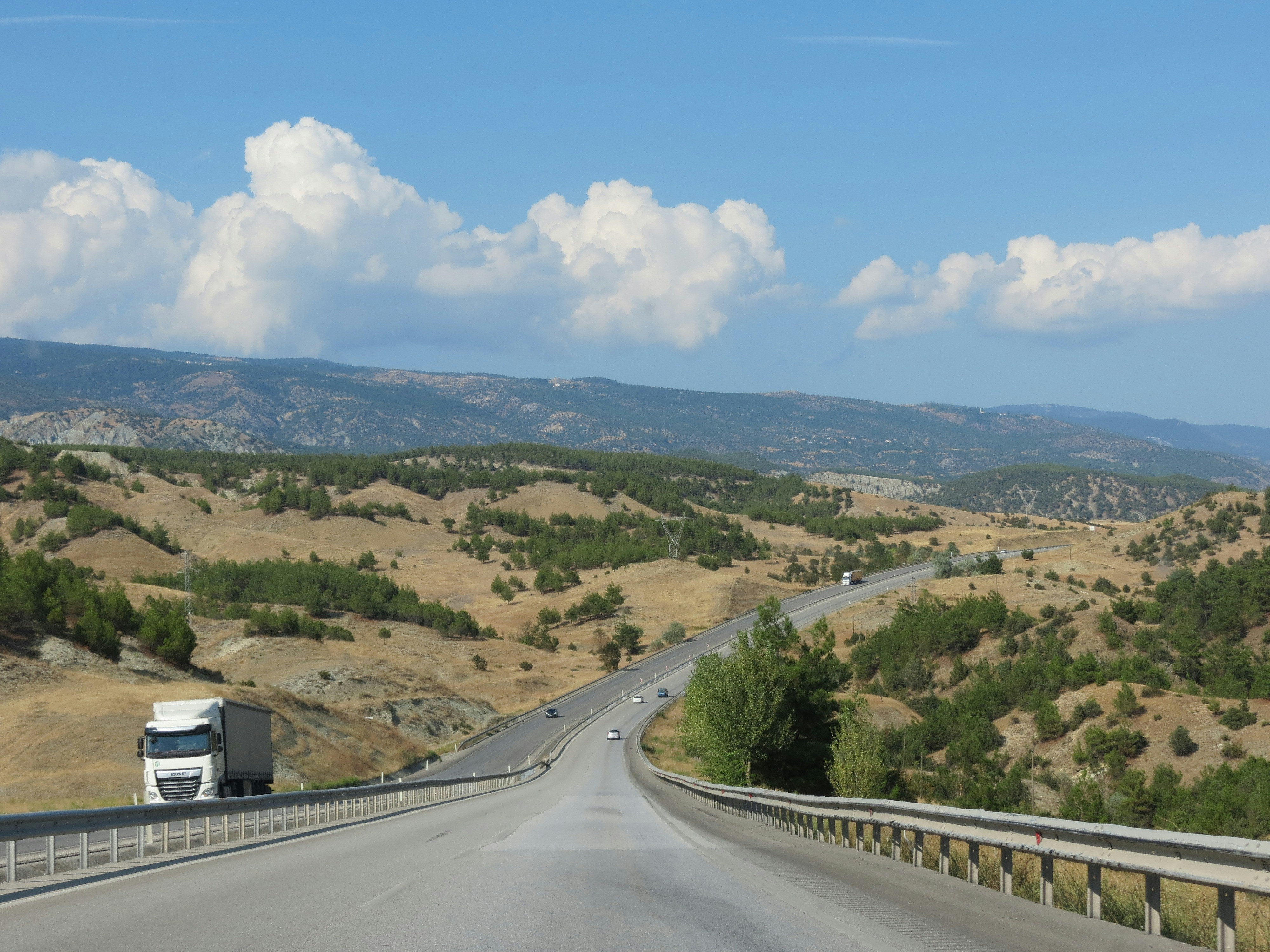 a truck driving down a road with mountains in the background