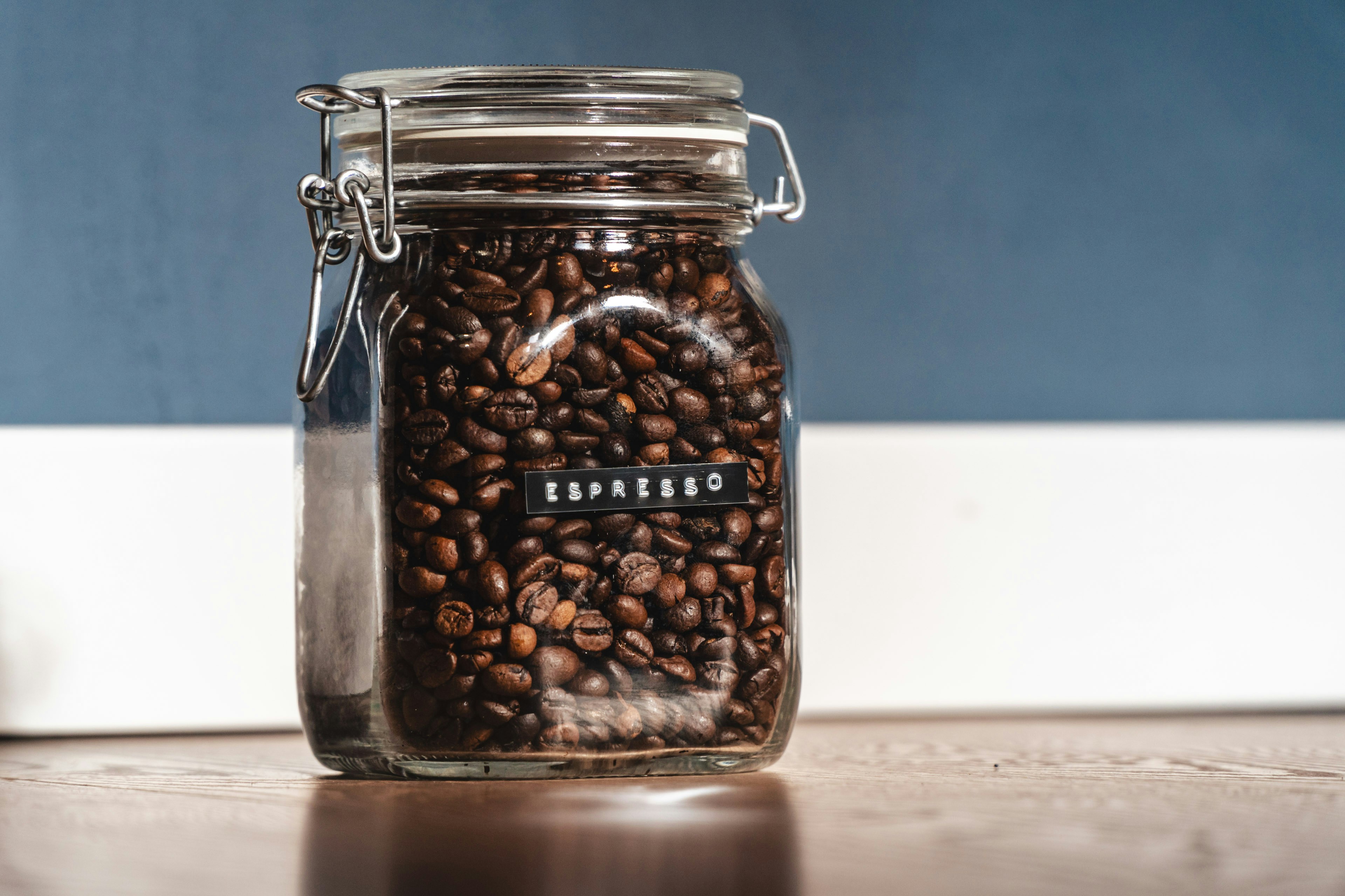 ein mit Kaffeebohnen gefülltes Glas, das auf einem Tisch steht