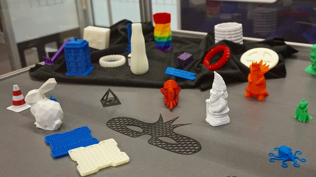 a table topped with lots of plastic toys, Design for Additive Manufacturing (DFAM) comprises a set of guidelines and best practices essential for designers and engineers to achieve optimal outcomes in printed part designs. Additive Manufacturing (AM), commonly referred to as 3D printing (3DP), encompasses various technologies such as stereolithography (SLA), selective laser sintering (SLS), fused deposition modeling (FDM), direct metal laser sintering (DMLS), among others. DFAM encompasses considerations related to the chosen printing technology, part geometry, materials selection, and any necessary.
