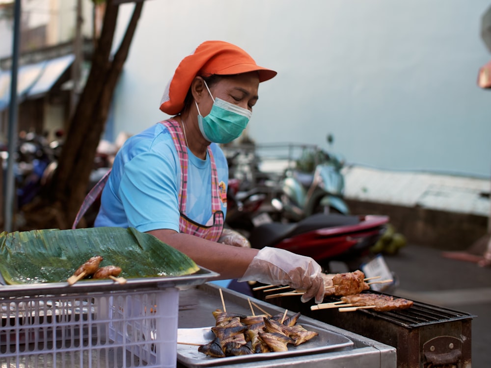 a person wearing a face mask cooking food on a grill