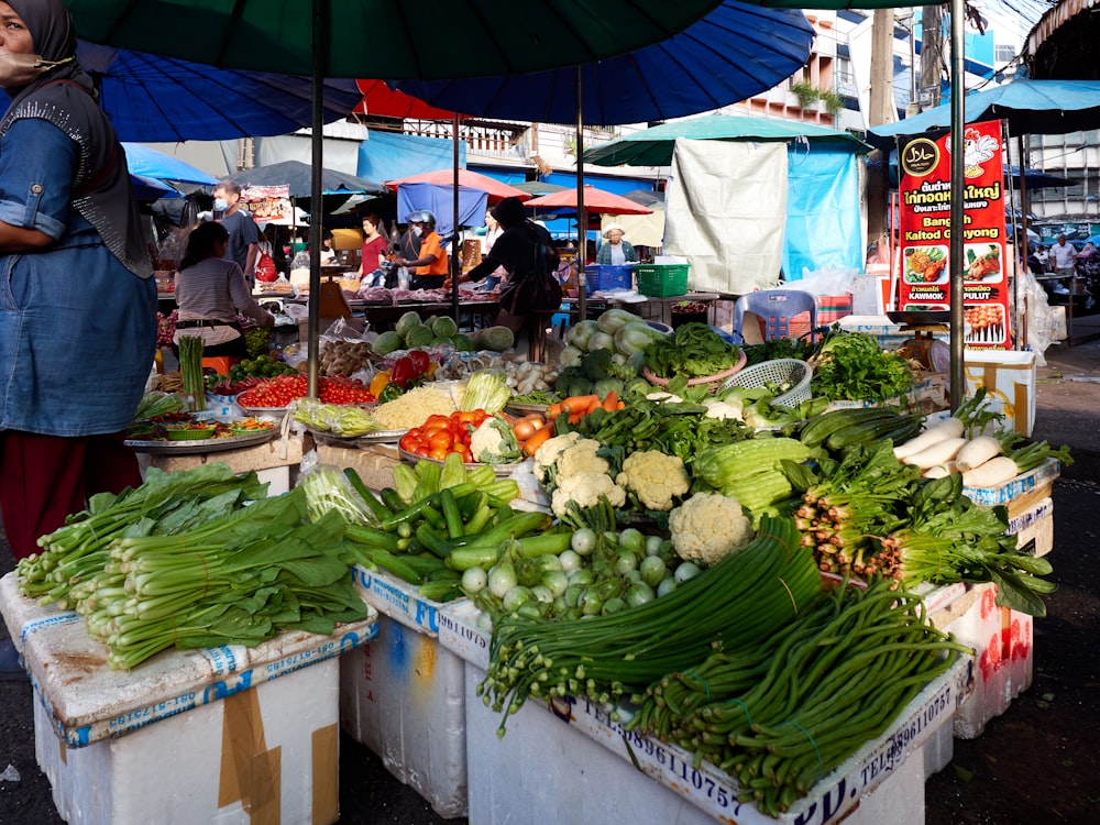 a woman standing in front of a table filled with vegetables