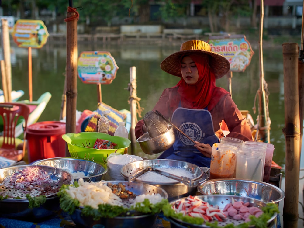 帽子をかぶった女性が船の上で食べ物を売っている