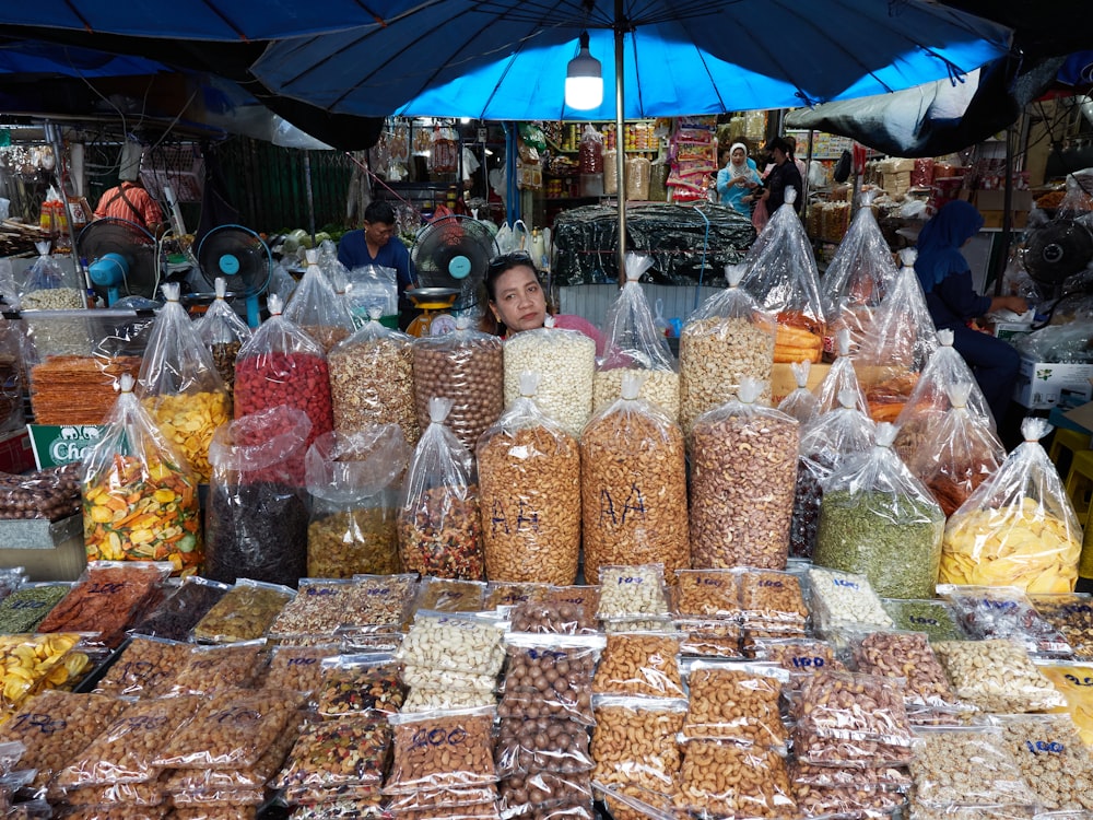 a woman sitting behind a table filled with bags of food