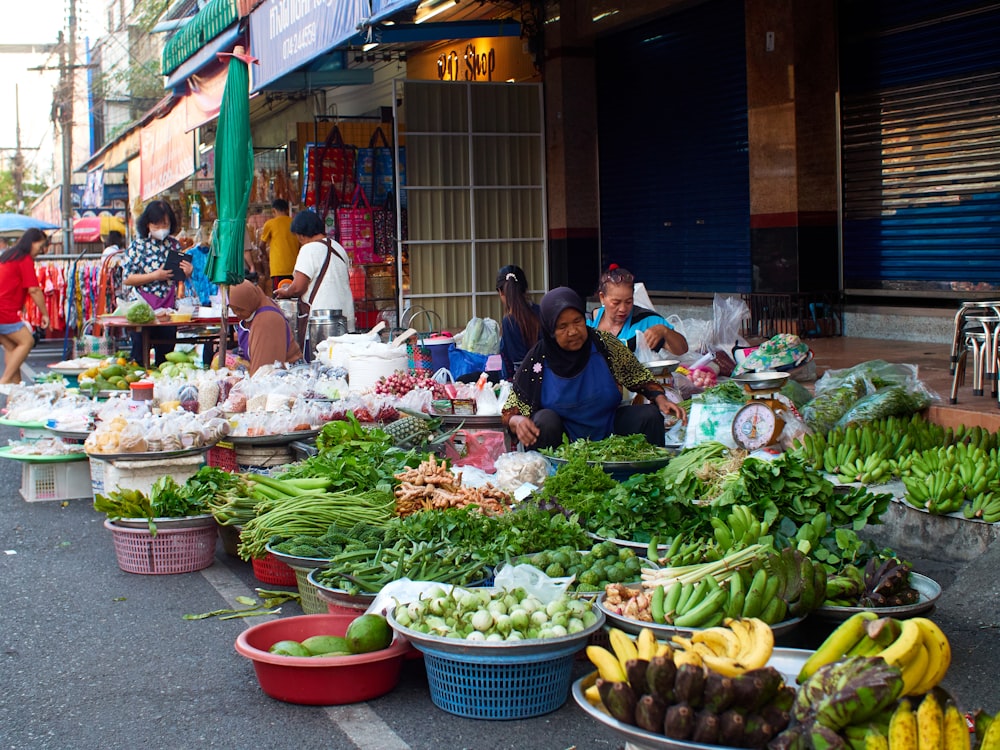 a woman sitting in front of a table filled with lots of vegetables