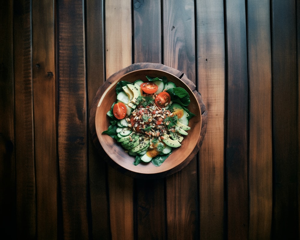 a wooden bowl filled with a salad on top of a wooden table