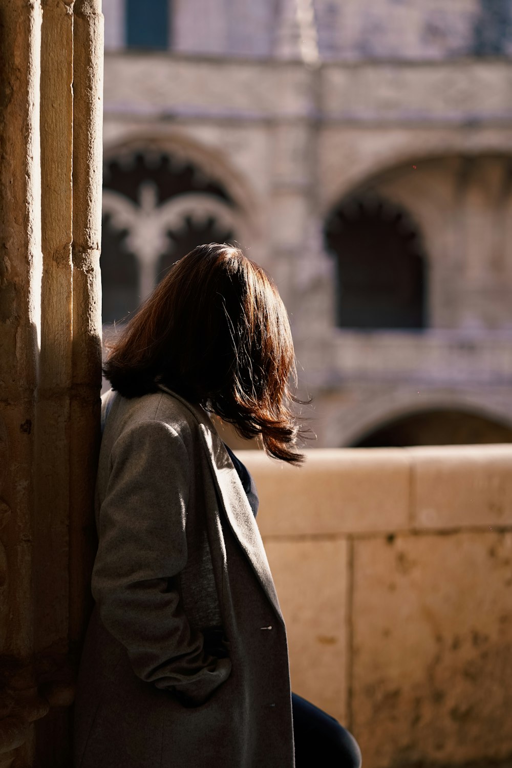 a woman leaning against a pillar in front of a building