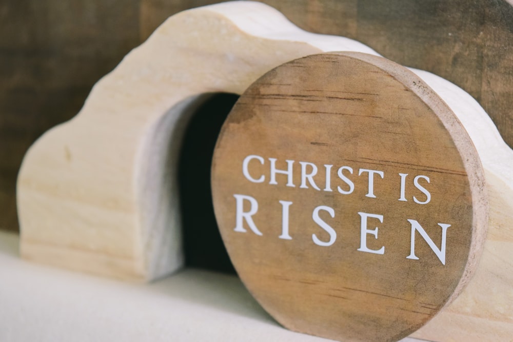 a wooden sign that says christ is risen