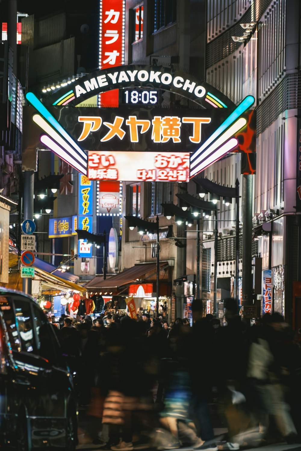 a group of people walking down a street next to tall buildings