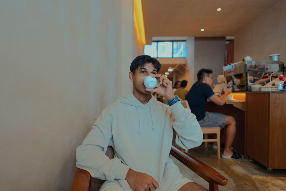 a man sitting in a chair drinking from a cup