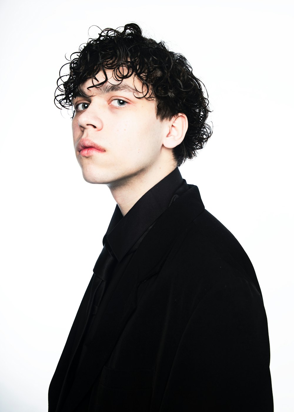 a young man with curly hair wearing a black shirt
