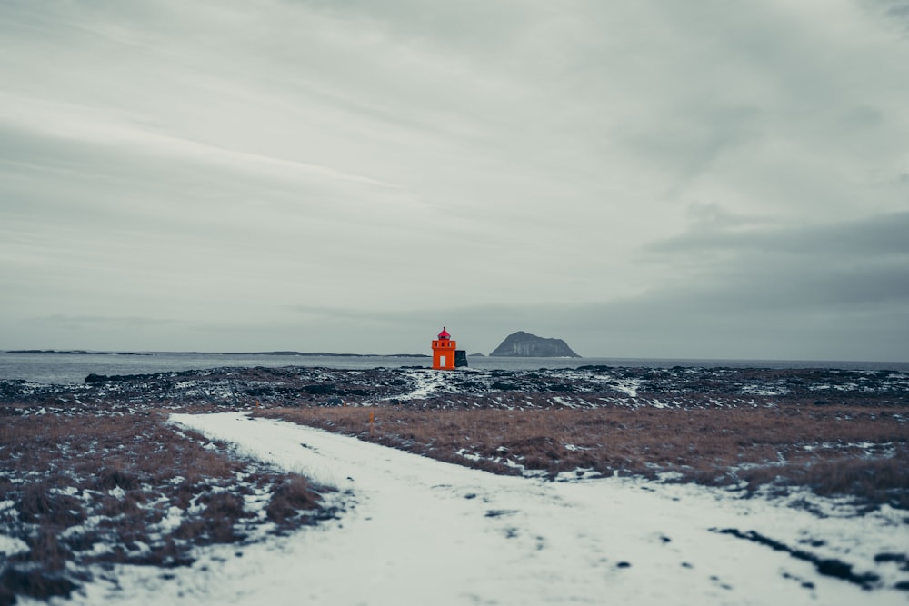 a person in an orange jacket standing on a snowy path