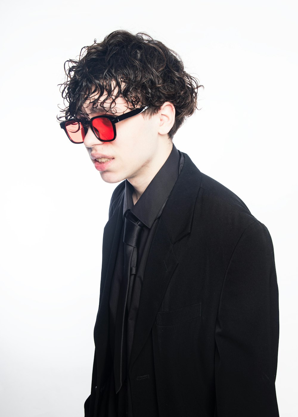 a man with curly hair wearing red sunglasses