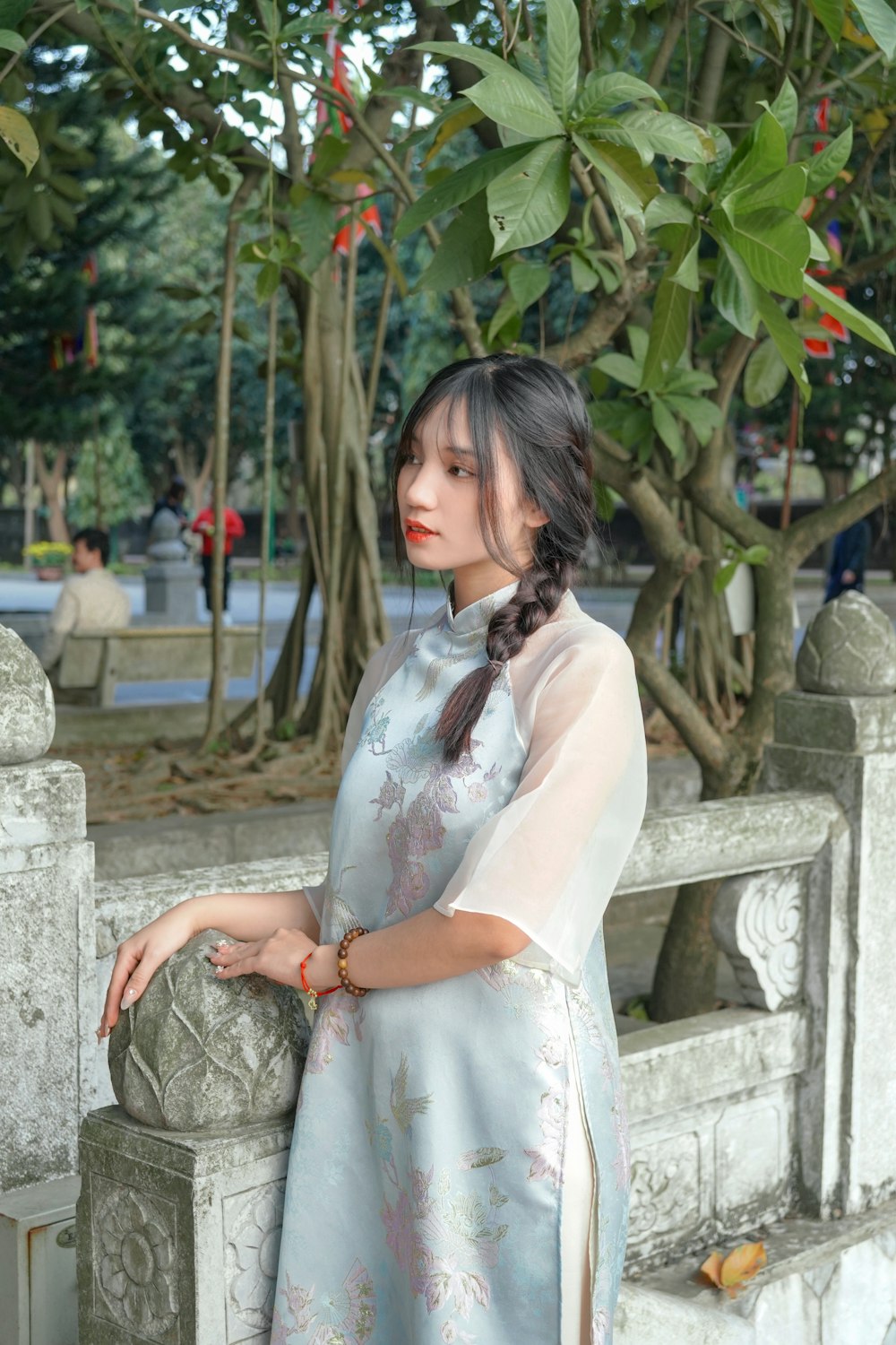 a woman standing next to a stone wall