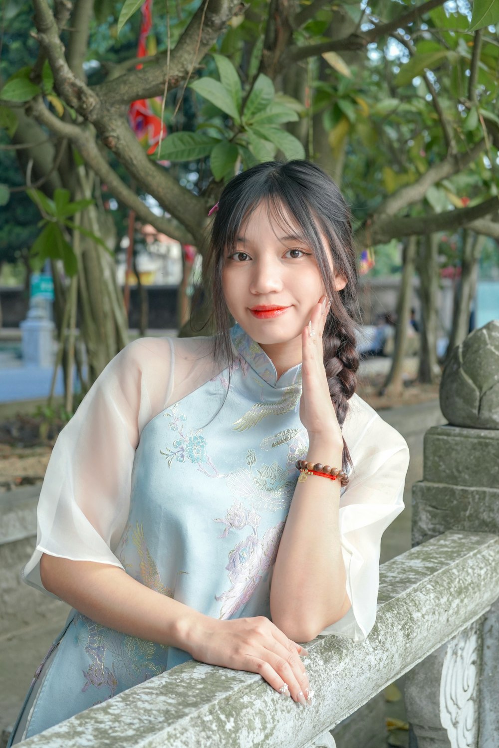 a woman leaning on a fence posing for a picture