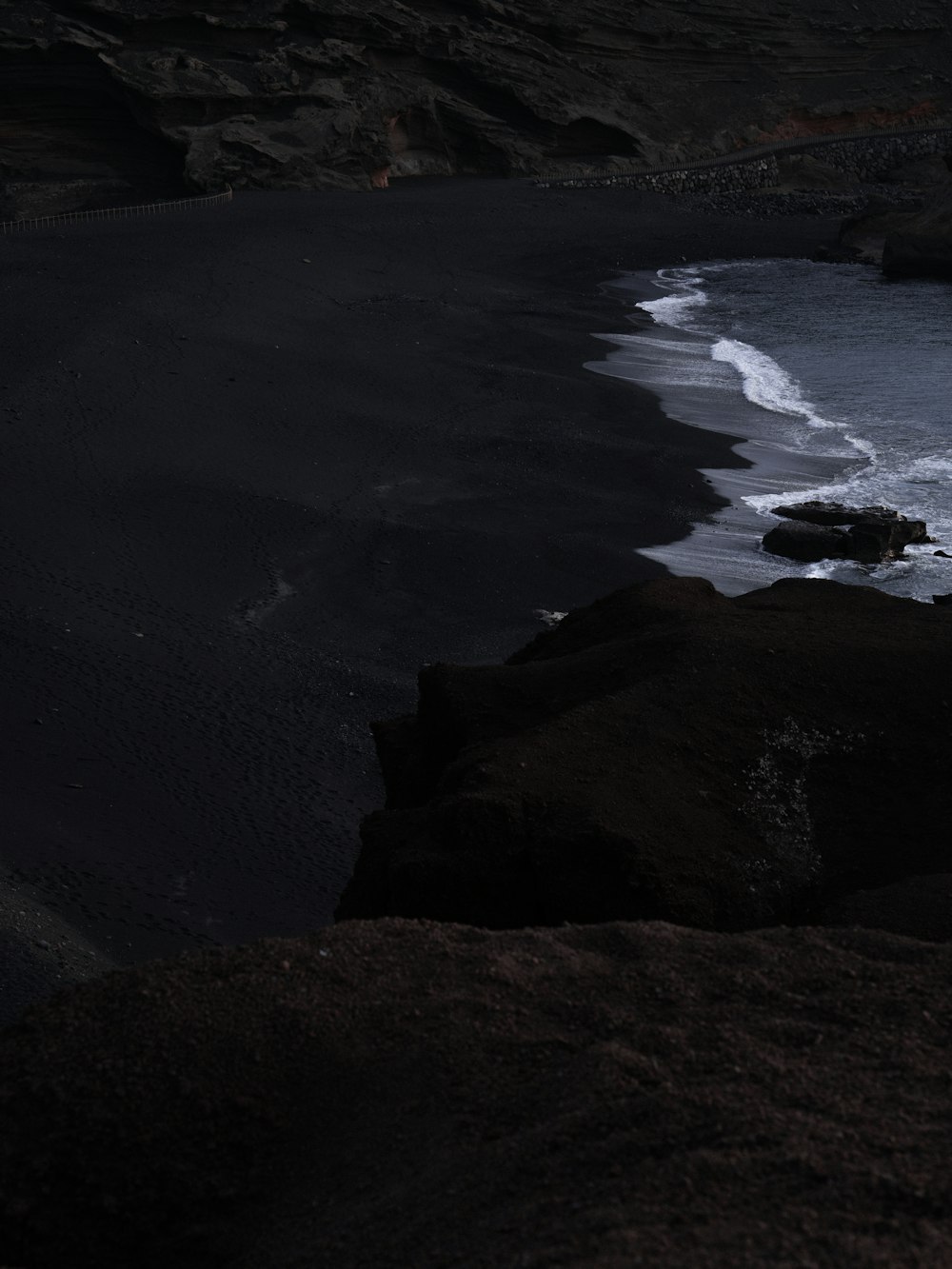 a black sand beach with waves coming in to shore