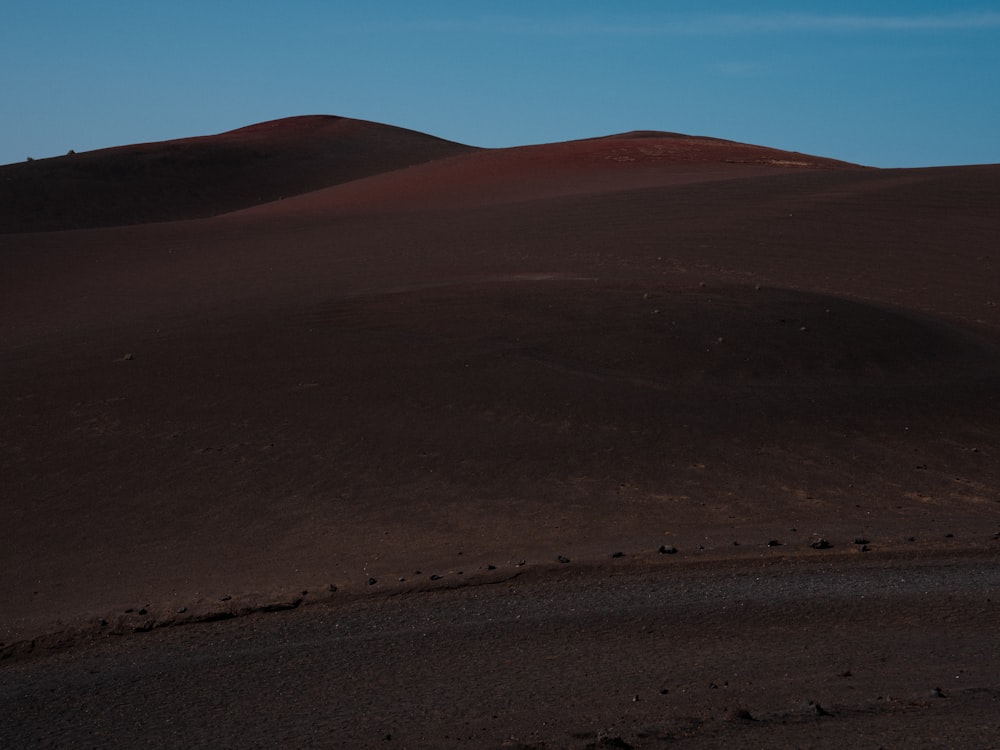 a hill covered in sand with a blue sky in the background