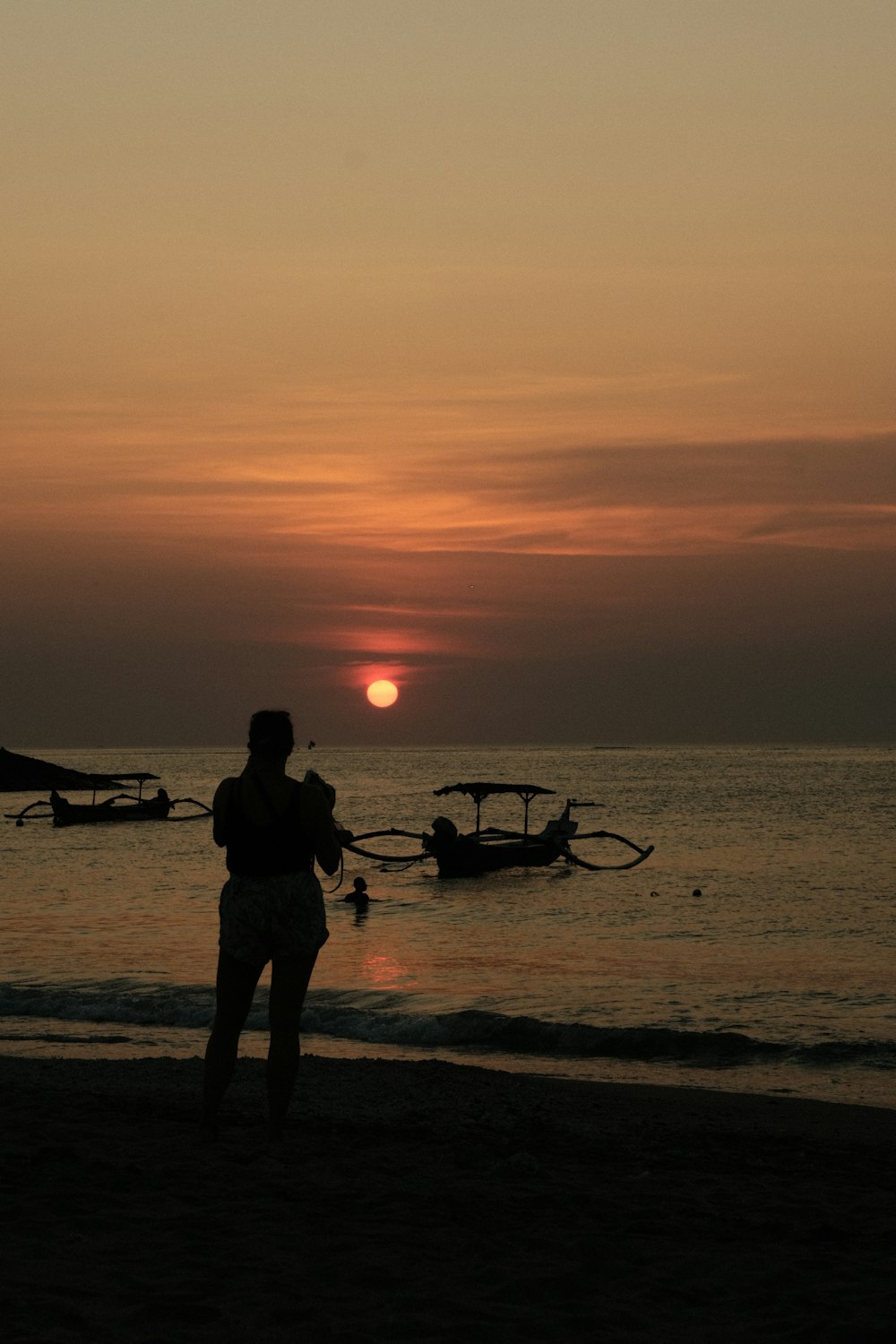 a woman standing on top of a beach next to the ocean