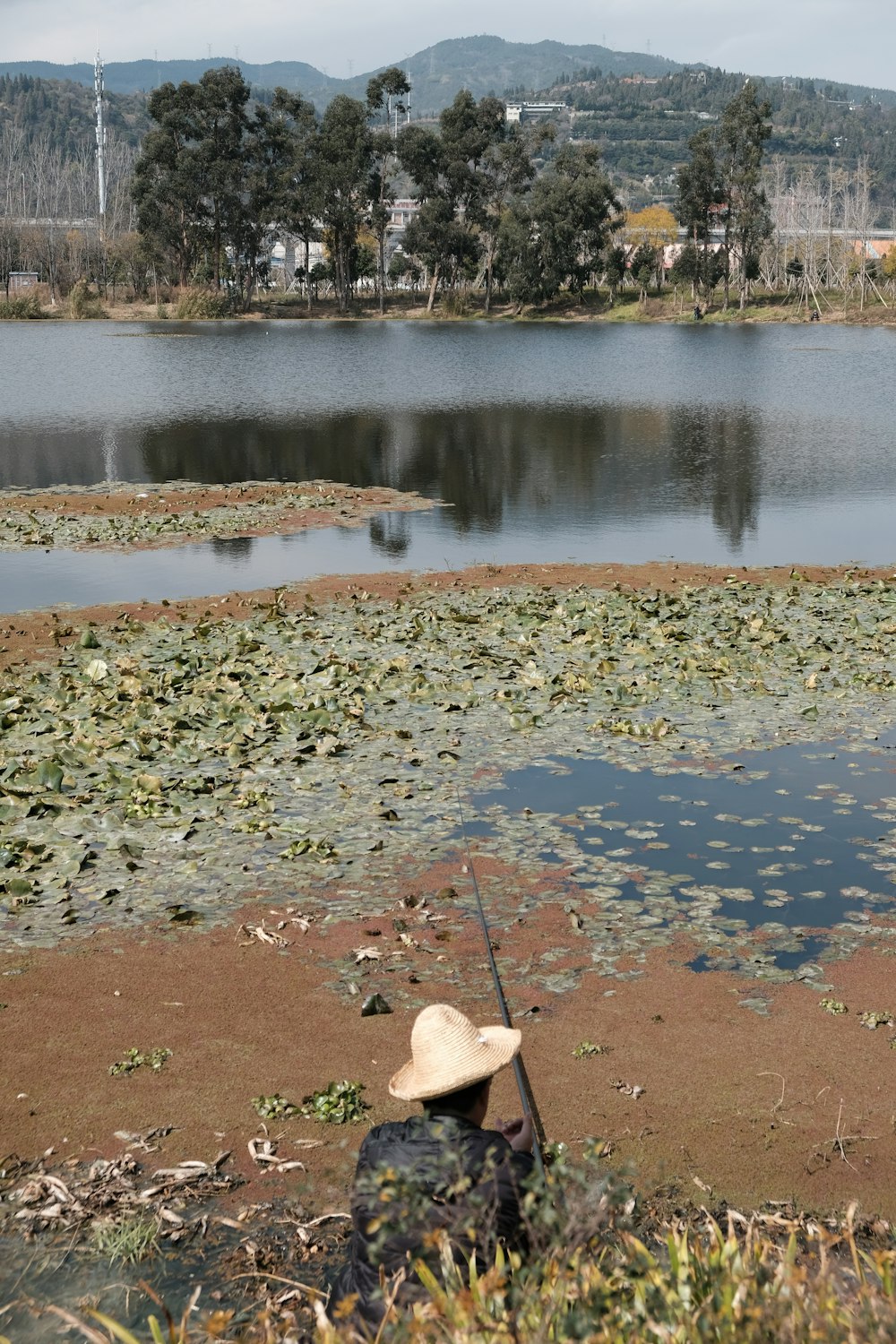 a person with a hat is fishing in a lake