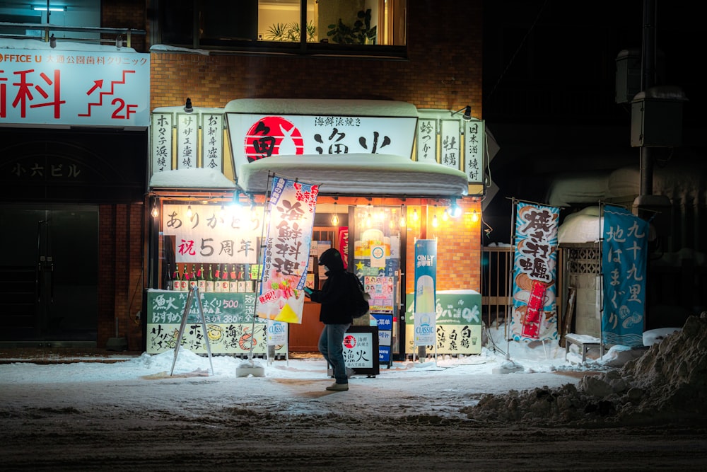 a woman standing in front of a store at night