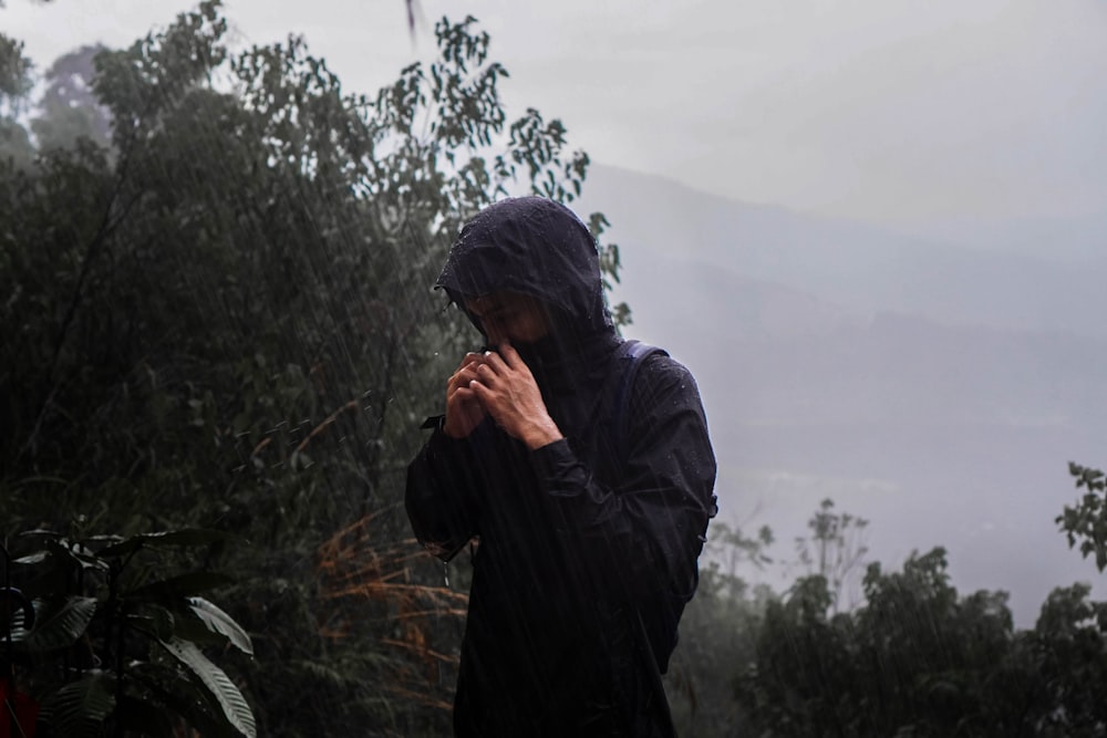 a person in a raincoat standing in the rain