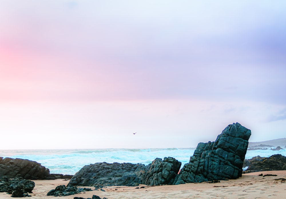 a large rock formation on a beach near the ocean