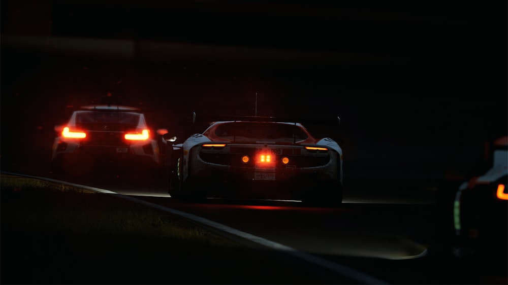 a couple of cars driving down a street at night